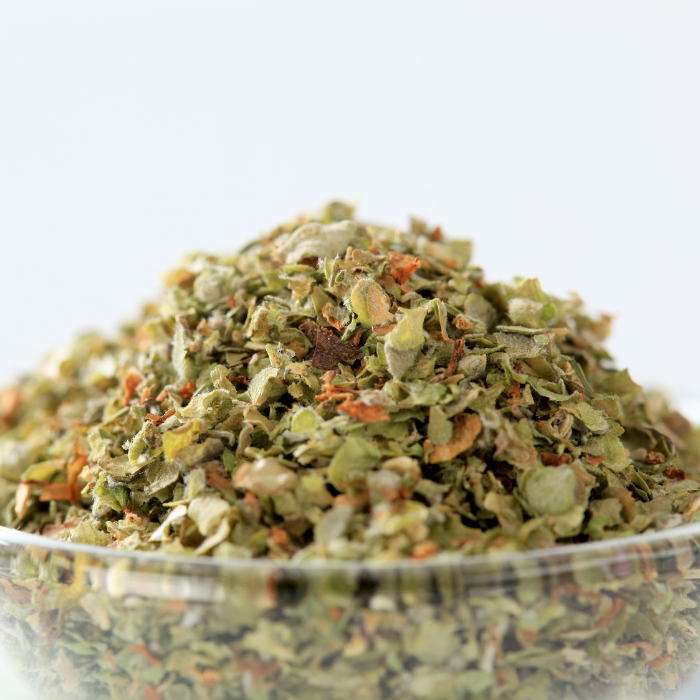 Organic marjoram in a clear glass bowl with a white background