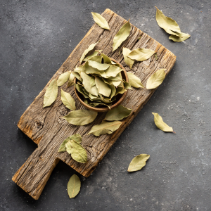 Dried bay leaves laid out on a wooden board with a grey background