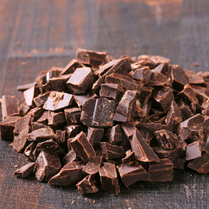 A pile of dark chocolate chunks on a wooden surface