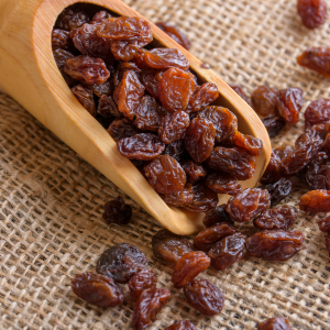 Thompson raisins in a wooden scoop with a burlap background