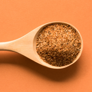 Wooden spoon filled with cajun spices with an orange background