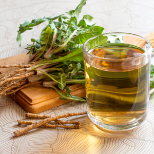 Dandelion root on a cutting board next to a cup of dandelion tea