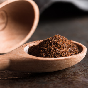 Wooden spoon filled with ground cloves with another wooden spoon in the background