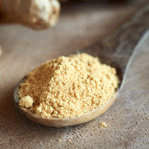 A wooden spoon filled with ground ginger powder
