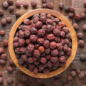 A wooden bowl filled with dried hawthorn berries