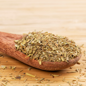 A wooden spoon full of italian seasoning with a wooden background