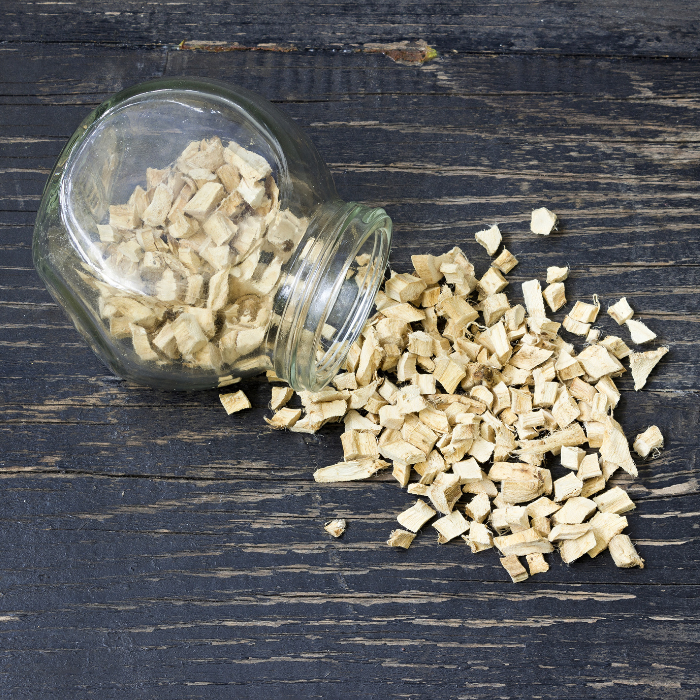 Dried ginger root in a glass jar on a dark wooden surface