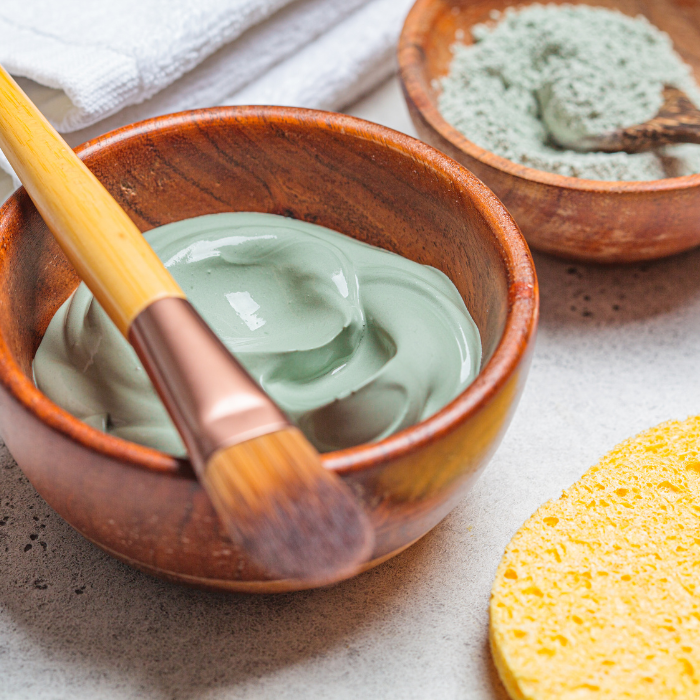 French green clay mask in a wooden bowl with a makeup brush next to a wooden bowl filled with french green clay