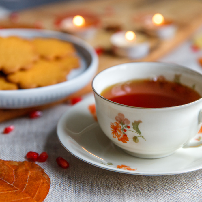 Gingerbread black tea in a teacup next to gingerbread and candles