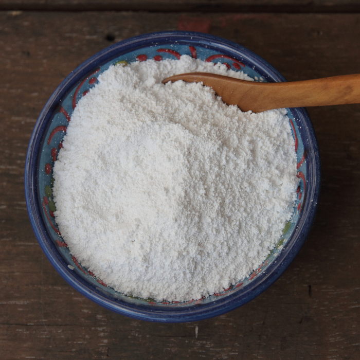 Kaolin clay in a blue ceramic bowl on a wooden surface