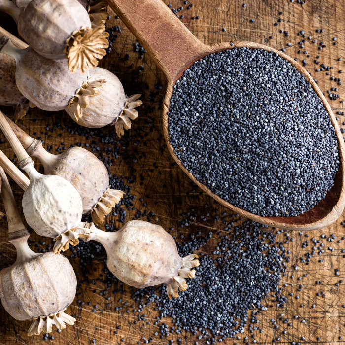 Poppy seeds in a wooden spoon on a wooden surface