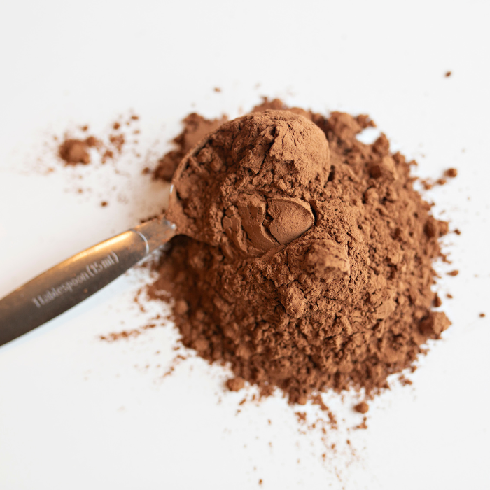 Cocoa powder on a white background with a metal spoon