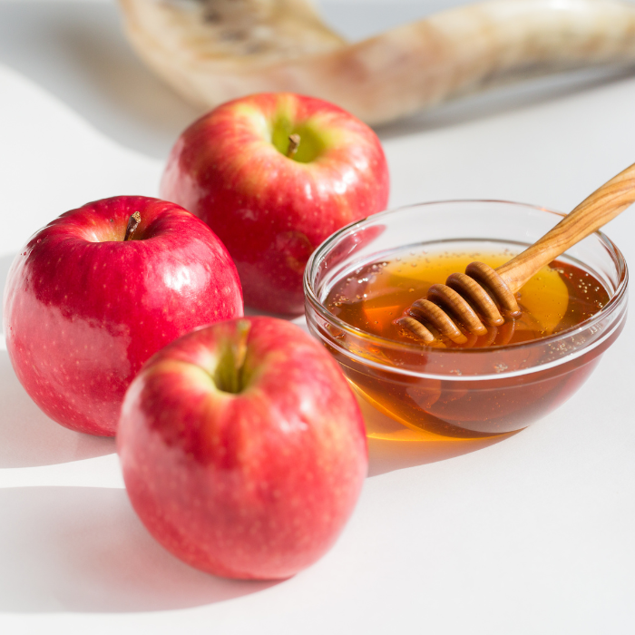 3 apples next to a small glass bowl of bee mindful hunnie