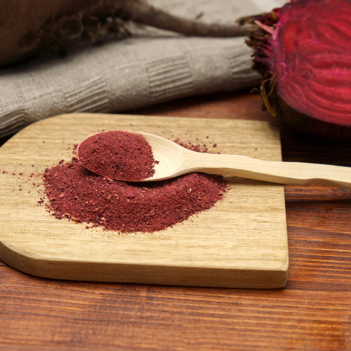 Beet root powder on a cutting board next to a beet on a wooden table