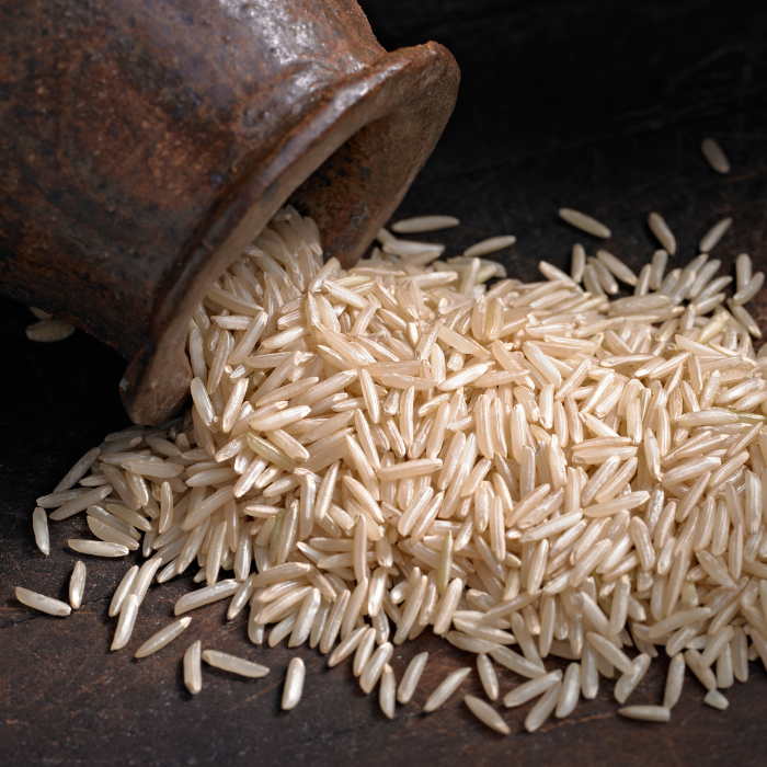 Brown basmati rice coming out of a metal pot onto a dark metal surface