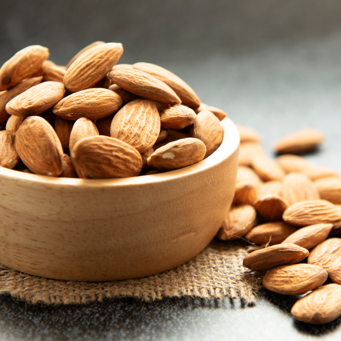 Whole almonds in a wooden bowl on top of burlap