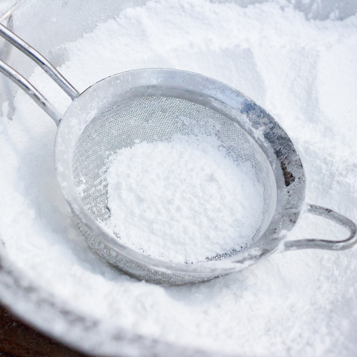 Icing sugar with a sieve in a metal bowl