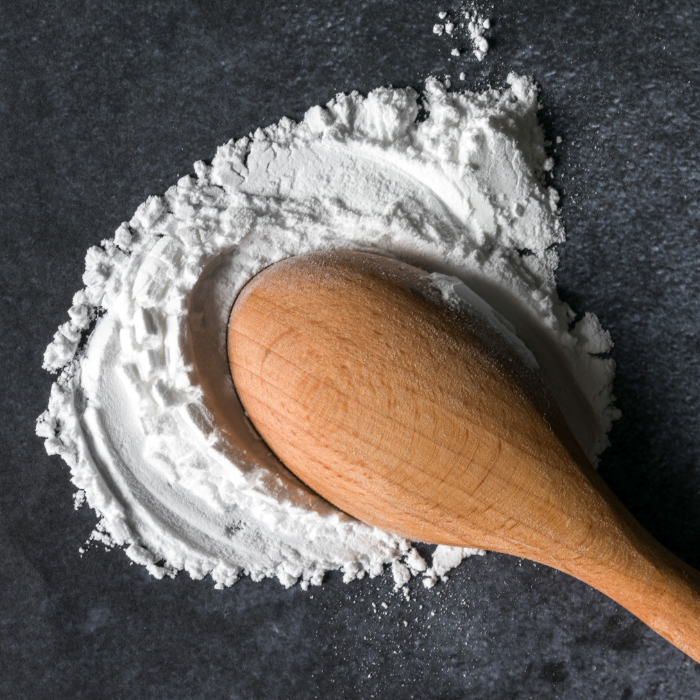 Cream of tartar on a grey surface with a wooden spoon