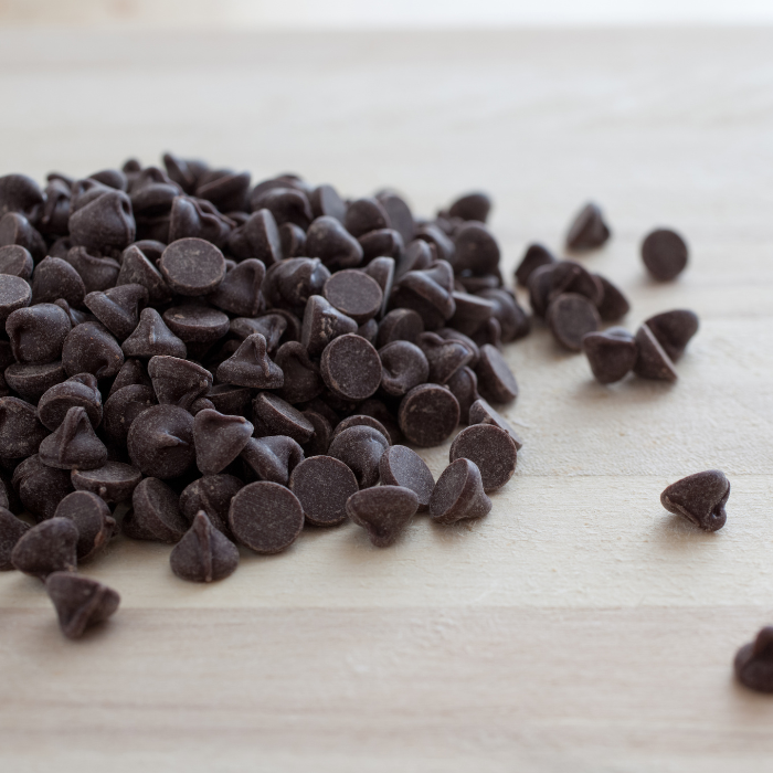 Dark chocolate chips on a light wooden surface