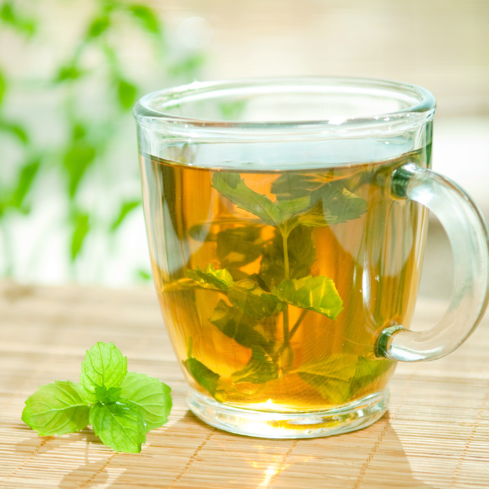 Spearmint tea steeping with fresh spearmint leaves on a bamboo mat