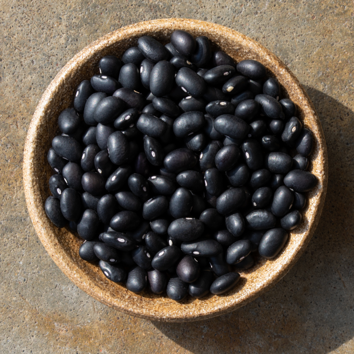 Dried black beans in a bowl on a concrete background