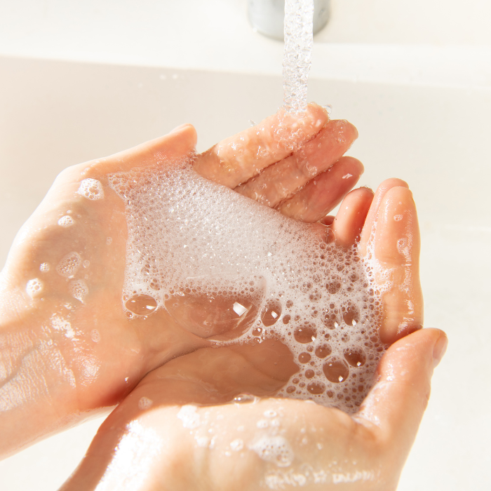 Soap suds in hands with water running and a white background