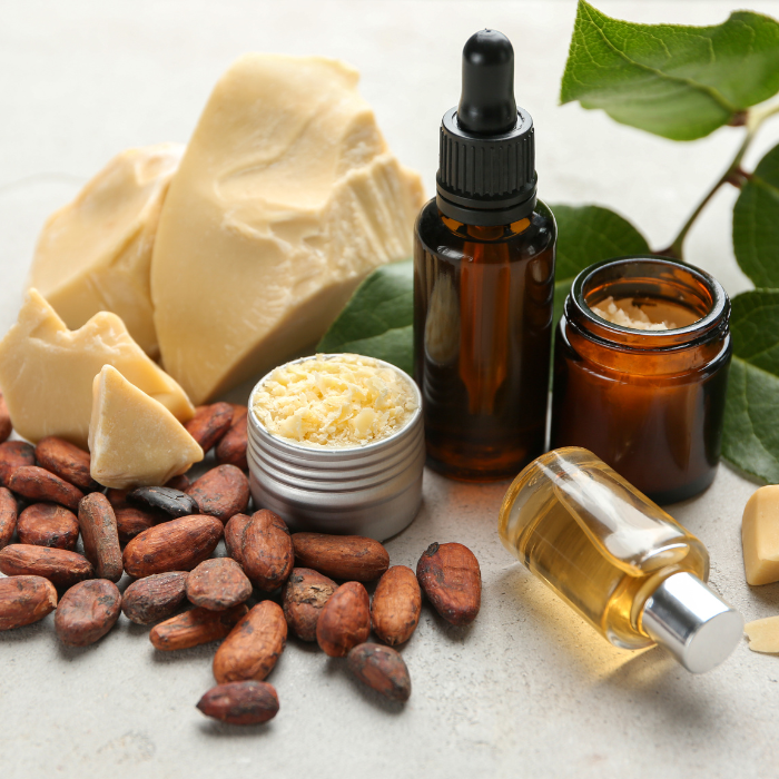 Chunks of cocoa butter next to an assortment of cocoa butter products, cocoa beans, and leaves