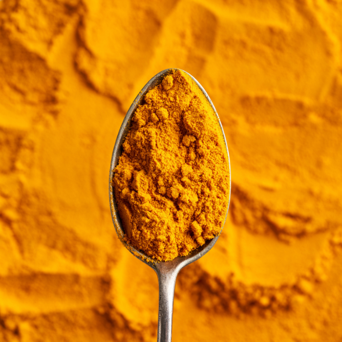 Turmeric powder spread out on a surface with a metal spoon