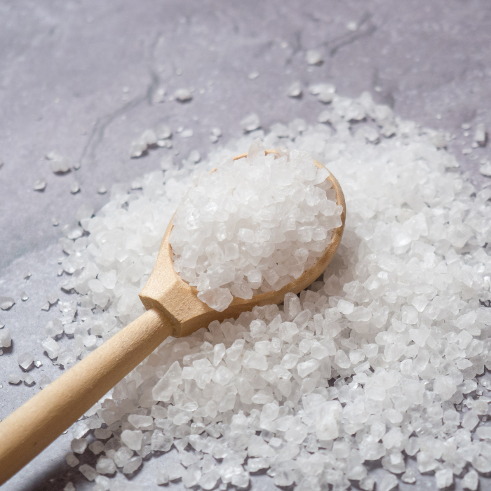 Dead sea salt in a wooden spoon on a grey surface