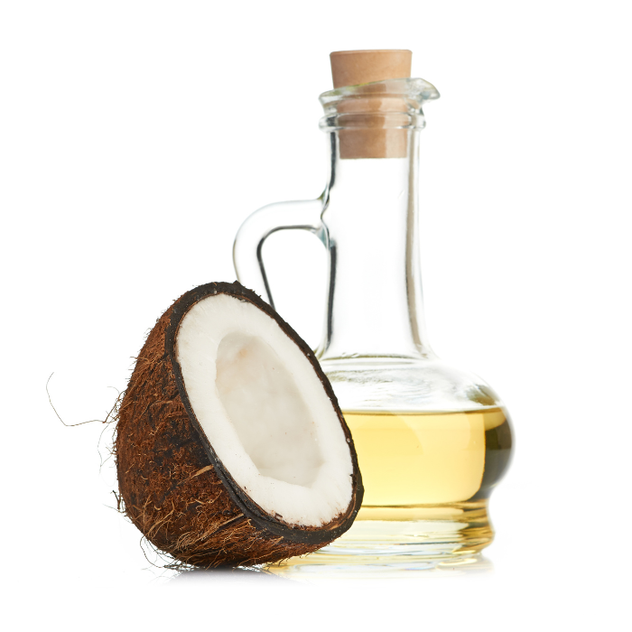 MCT oil in a glass bottle next to a coconut with a white background