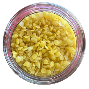 A clear glass jar filled with unrefined beeswax pellets with a white background