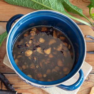 Comfrey root in water in a blue pot with a wooden background