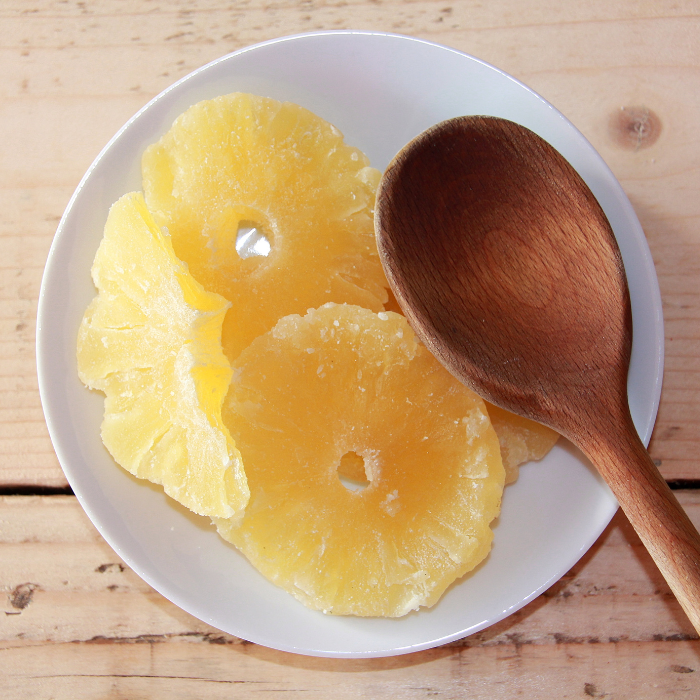 Pineapple rings in a white bowl with a wooden background