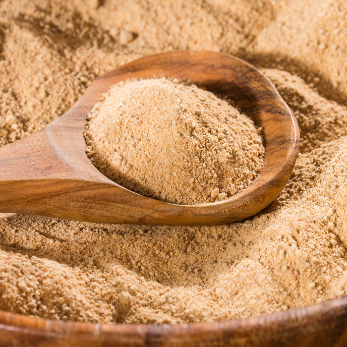 Maca powder in a wooden bowl with a wooden spoon