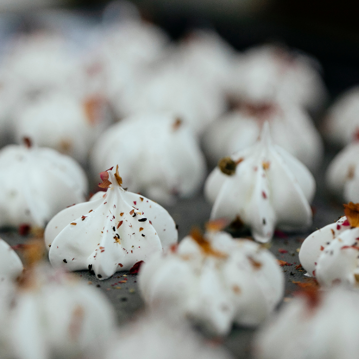 A baking sheet covered in meringue dollops 