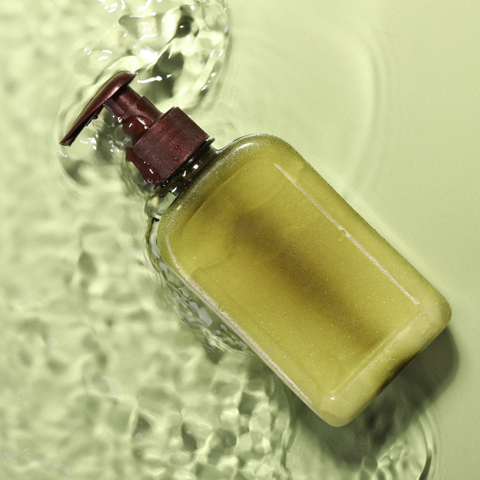 A glass bottle with a pump surrounded by mild facial cleanser gel