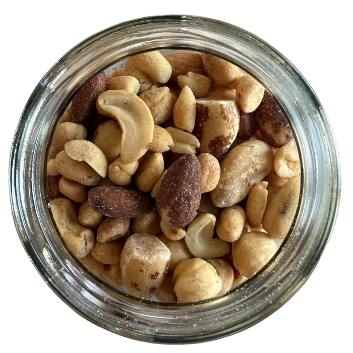 Mixed nuts with peanuts in a clear glass jar with a white background