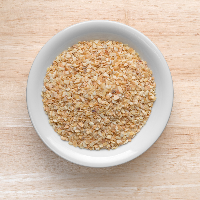 Organic minced garlic in a white bowl on a wooden background