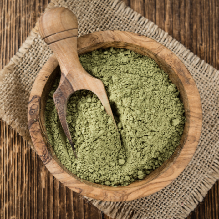 Stevia leaf powder in a wooden bowl with a wooden spoon 