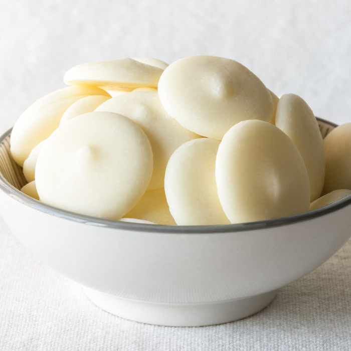 White chocolate wafers in a white ceramic bowl with a white background