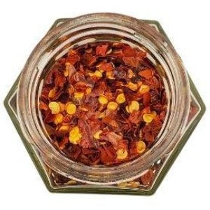 White background with a glass jar filled with Organic Chili Flakes.